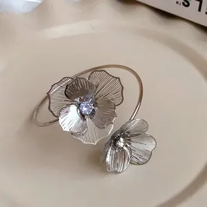 Detailed macro shot of an elegant silver open cuff bracelet with crystal flower motifs.