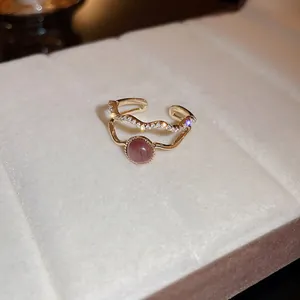 Detalle de anillo dorado vintage con gema rosa y pavé de pequeños cristales.