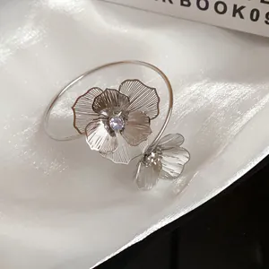 Detailed view of elegant silver floral open bangle with sparkling rhinestone center design.