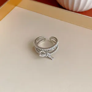 Primo piano di un elegante anello in argento con un delicato fiocco ricoperto di perle