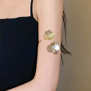 Detailed view of an elegant gold flower arm cuff with rhinestones on a female model