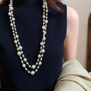 Detail shot of an elegant multi-layer faux pearl long necklace on a black turtleneck.