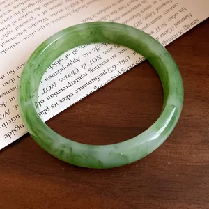 Dettaglio di un braccialetto rigido in resina marmorizzata verde lucida su legno
