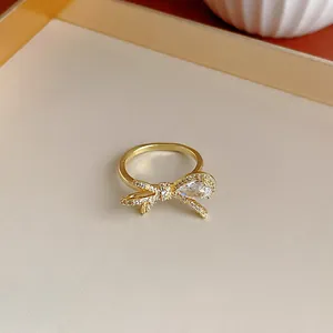 Dettaglio macro di un anello a fiocco placcato oro con zirconi scintillanti.