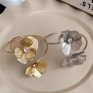 Detailed view of elegant gold and silver flower open bangles featuring sparkling crystal centers