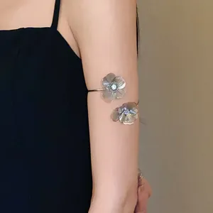 Elegant silver flower arm cuff with sparkling rhinestone center on female model