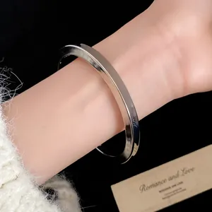 Elegante bracciale rigido argento lucido minimalista mostrato su un polso in dettaglio