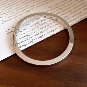 Dettaglio ravvicinato di un bracciale a cerchio lucido in argento dal design moderno.