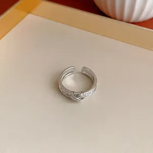 Primo piano di un anello geometrico d'argento con design a croce in zircone scintillante