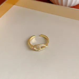 Dettaglio di un anello geometrico placcato in oro con zirconi scintillanti.