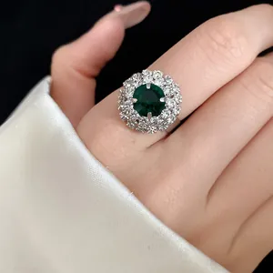 Vintage floral ring with a central emerald green stone surrounded by sparkling crystals.