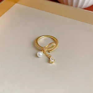 Primo piano di anello a fiocco placcato oro con ciondoli perla e zircone a goccia.
