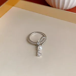 Dettaglio macro di un anello a fiocco in zircone argento con perla e pietra a goccia.