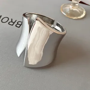 Detailed macro view of a wide asymmetric silver-toned polished open bangle.