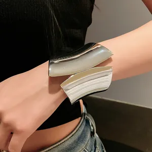Detail of a wide asymmetric open bangle with silver-tone edges and white inlay.