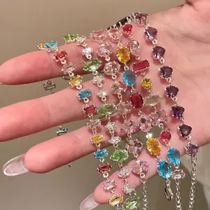 Close-up of multiple colorful zircon bracelets with various gemstone cuts on a hand