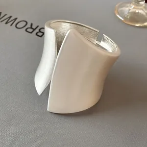 Close-up of wide asymmetrical matte silver cuff bracelet with brushed metal texture