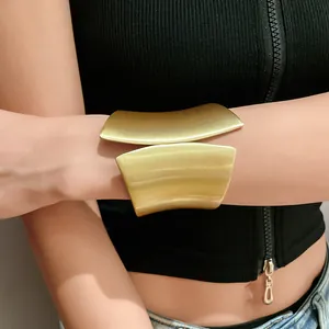 Detail shot of wide asymmetric gold open cuff bracelet with brushed metal finish