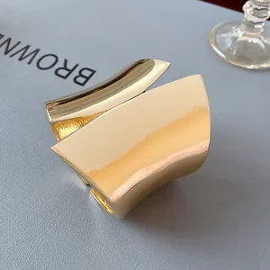 Detail view of a wide asymmetric gold open cuff bracelet with a polished finish.