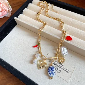 Detail of gold link necklace with heart, chili, and pearl pendants in a jewelry box