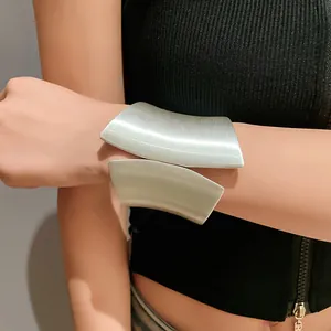 Detail view of a stylish wide asymmetrical silver open cuff bracelet worn on a female wrist