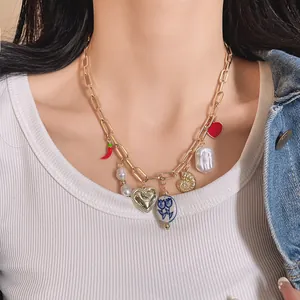 Detail view of a chunky gold chain necklace with mixed charms like chili and pearls.