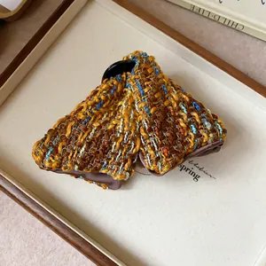Close-up of tweed triangular hair claw clip with autumn brown and blue woven texture.