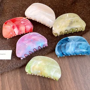 Detail view of assorted colorful marble acrylic hair claw clips on rustic background
