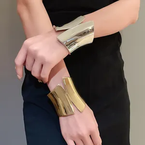 Detail shot of wide asymmetrical open cuff bracelets in polished gold and silver finishes