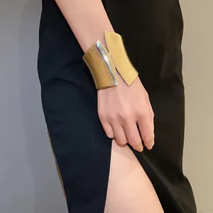 Close-up of a stylish wide asymmetric golden cuff bracelet worn with black dress