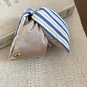Close-up of elegant satin hair claw clip with blue striped bow and love metal tag