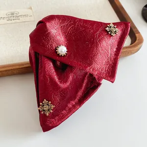 Close-up of wine red triangular hair claw with vintage metal ornaments and pearl.