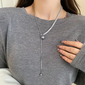 Close-up detail view of elegant silver long necklace with grey pearl drop on model