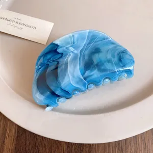Macro view of blue marble acrylic hair claw clip with elegant swirl pattern