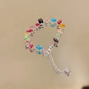 Macro detail of a colorful zircon bracelet with vibrant gems reflecting on a mirror surface.