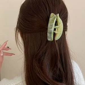 Close-up view of a green marbled acrylic hair claw clip used on long brown hair