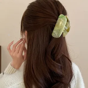Close-up detail of a green marbled acrylic hair claw clip styling a half-up hairstyle