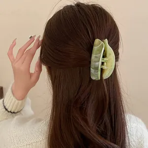 Back view of a woman wearing a green marbled acrylic oval hair claw clip.