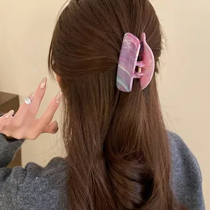 Detail view of a marbled purple acrylic hair claw clip styled on long wavy brown hair