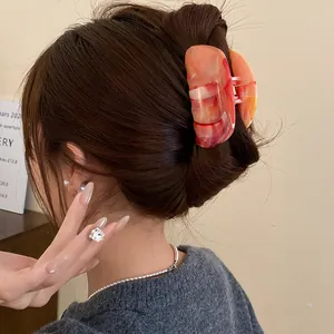 Detail view of an elegant marbled acrylic hair claw clip used on a stylish hair bun