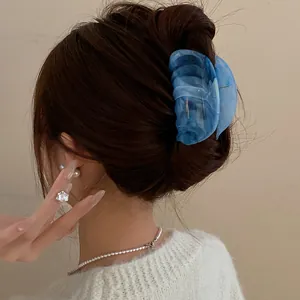 Elegant detail showing a blue marbled acrylic hair claw clip on styled brown hair