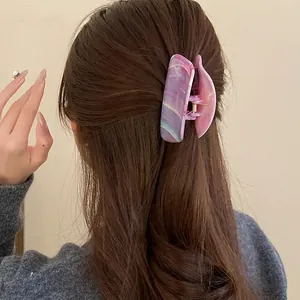 Detail of a purple marble acrylic hair claw clip on long brown hair in a lifestyle setting