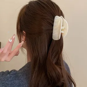 Detailed view of an elegant marbled acrylic hair claw clip worn on long brown hair