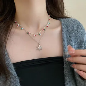 Detail view of a double-layered silver snowflake necklace with red and green beads