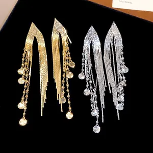 Detailed view of long gold and silver tassel earrings with small round discs on black velvet.