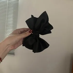 Dettaglio ravvicinato di un grande fermaglio per capelli in raso nero con fiocco elegante