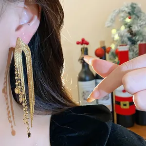 Detailed macro view of long 18k gold plated tassel earrings worn by a model