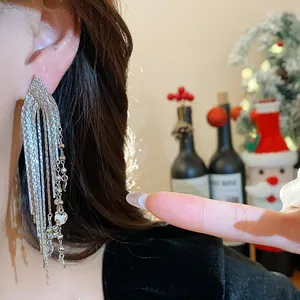 Detail of silver-colored tassel drop earrings with intricate layered chain design