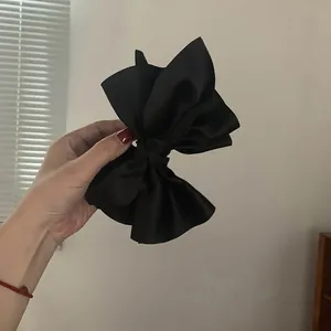 Primo piano di un'elegante clip a fiocco in raso nero tenuta in mano per capelli