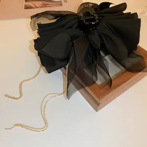 Elegant black fabric bow hair claw clip featuring a long rhinestone tassel detail accessory